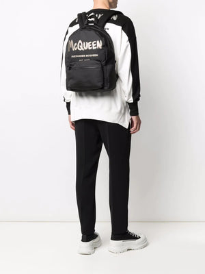 Japanese: MCQUEENの大胆な落書きデザインが特徴の黒色メトロポリタン印刷バックパック（男性用）